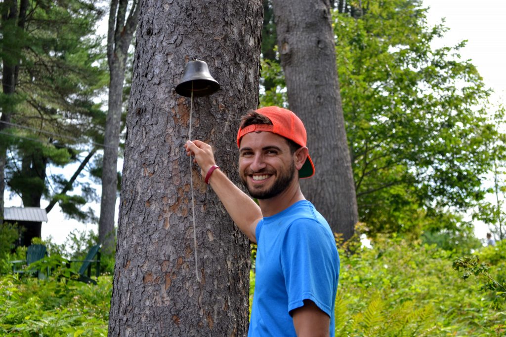 Camp counselor ringing bell on tree