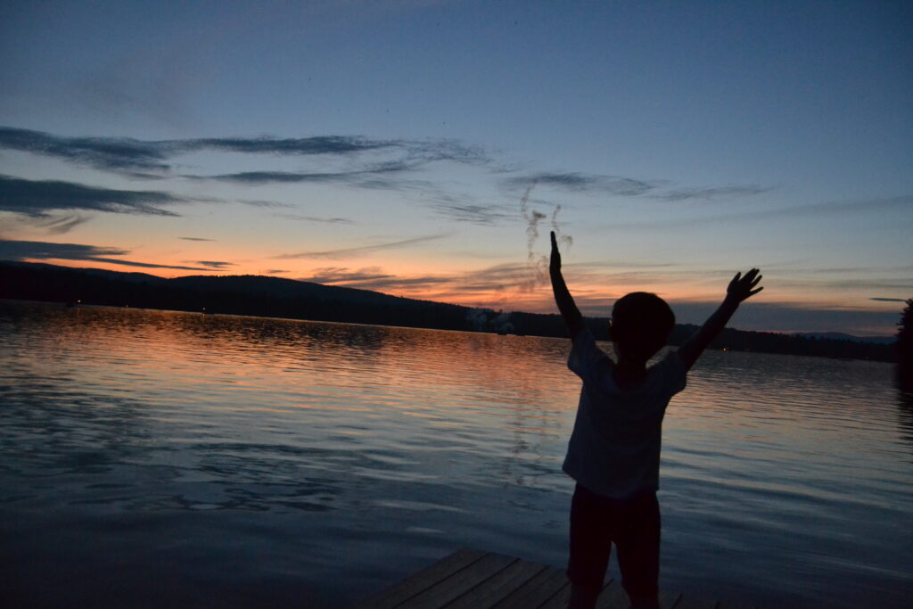 A child standing with his hands up watching fireworks.