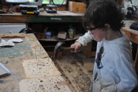 A camper hitting a nail in the woodshop.