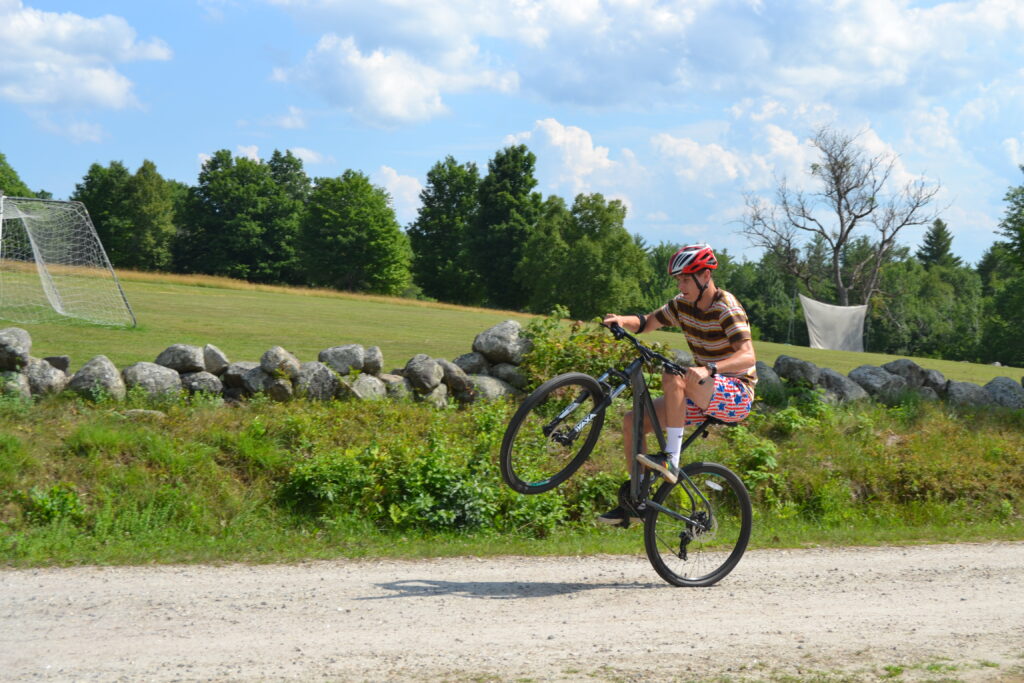 A camper doing a wheelie on his mountain bike.