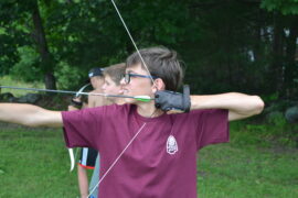 A camper shooting a bow and arrow.