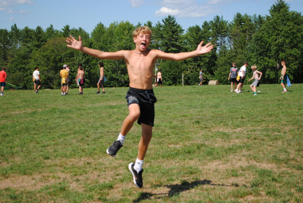 Camper jumping up with his arms out, excited for second session to begin.