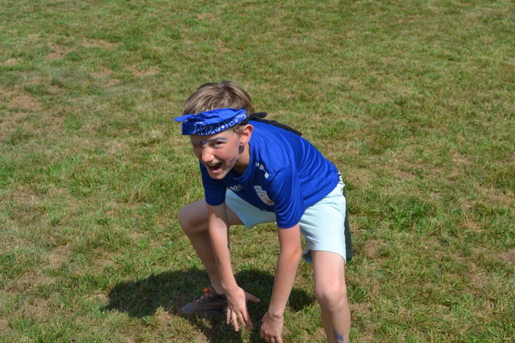 A camper crouching down to play a camp game.